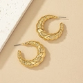 Dettaglio ravvicinato di orecchini a cerchio dorati a forma di C con texture a treccia - Oro