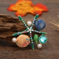 Broche de estrella de mar verde con perlas blancas y conchas sobre fondo de madera - Verde