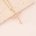 Dettaglio della collana a croce dorata con cristalli di zircone rosa su una pietra - Rosa