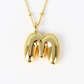 Close-up of a polished golden bubble letter M pendant on a fine link necklace chain - Letter M