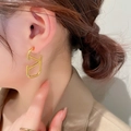 Close-up of golden C-shaped letter earrings on a model showing a luxury design - Gold Letter