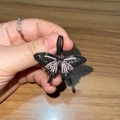 Mini vlinder hanger ketting met zwarte en zilveren strass steentjes op houten tafel - Zwart-Roze Vlinder + Torsieketting