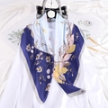 Pañuelo de seda azul con estampado floral y conchas sobre un bolso y ropa blanca - Azul Conchas Floral