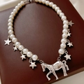 Detail of pearl necklace featuring silver horse pendant and stars on leather jewelry box - Silver-Beige