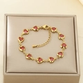 Pulsera de eslabones dorados con corazones de cristal rojo en un joyero beige - Pulsera de Corazón Rojo (KB204098-SXSJ)