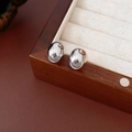 Nahaufnahme silberner ovaler Ohrstecker auf einer edlen Holz-Schmuckschatulle - Silber