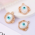 Detail of three vintage gold evil eye pendants with white opal and blue eye motifs - Oval with Border