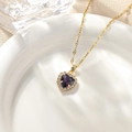 Macro shot of gold heart necklace with purple gemstone on a white ceramic plate - January - Violet