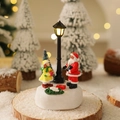 Close-up of glowing street lamp with Santa and girl figurine on a snowy base - Santa Claus