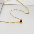 Dettaglio del pendente a cuore con gemma rossa su una catena in acciaio titanio oro - Zircone a Cuore Rosso