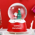 Close-up of a red base Christmas snow globe featuring Santa Claus and a pine tree - 80 Medium Music+Light / Santa - Waving