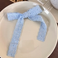 Detalle de lazo de encaje azul claro con bordado sobre un plato de cerámica crema - Lazo Azul