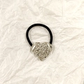 Black elastic hair tie with silver hammered heart-shaped metal charm on beige background - Silver Heart Liquid 3.5cm