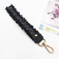Black woven bag strap with silver silk thread, leather trim, and gold tassel accessory - Black
