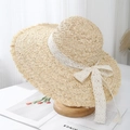 Close-up of raffia sun hat featuring white lace ribbon bow and frayed wavy brim detail - Beige - Frayed Edge Style