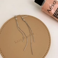 Macro shot of silver tassel drop earrings on a leather pad with minimalist snake chains - Silver