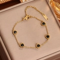 Pulsera de corazón en acero de titanio dorado con cinco dijes negros y marca S.STEEL - Oro Circonita Negra