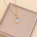 Detail of gold water drop necklace with light blue gemstone and white zircon accents - Light Blue