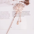 Rose gold floral hair pin with opal petals and crystal tassels on an open book - Rose Gold Cat's Eye Flower Tassel (FZ058)