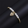 Detailed view of evil eye charm bracelet with white pearls and gold beads on display - CB00223 Pearl/Pearl Gold Bead Heart Eye