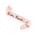 Pink satin Team Bride sash with rose gold foil lettering and ring icon on white backdrop - Champagne Team Bride
