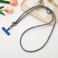 Close-up of gray woven crossbody phone lanyard with metal clasp and blue connector - Navy Blue
