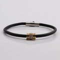 Dettaglio del bracciale in pelle nera con ciondolo in zircone dorato e chiusura magnetica - Nero/Argento