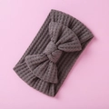 Detail view of a brown waffle-knit baby headband featuring a large bow on a pink background - Brown Bow (15)
