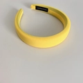 Detailed macro view of yellow sponge headband featuring handmade label and woven texture - Yellow