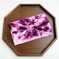 Pink and purple tie-dye wide yoga headband with central bow detail on wooden tray - Pink Purple Tie-dye