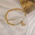 Dettaglio del bracciale con perle dorate e ciondolo a forma di orsetto con gemma rosa - Ciondolo Orso Rosa