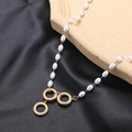 Elegant pearl necklace with golden twisted rings on gray silk and stone background - Triple Twisted Rings Pearl Necklace
