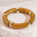 Close-up of golden glitter resin bracelet with polished metallic bead spacers on stone - Bracelet - Gold