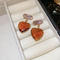 Primer plano de aretes de corazón con cristales naranjas y lilas en un joyero de terciopelo - Estilo pin de plata 925 / Marrón