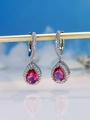 Macro shot of silver drop earrings with pear-cut pink gems and pavé zircon details - Rose Red