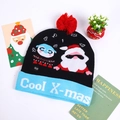 Detail of knitted Christmas hat with LED lights and Cool X-mas text on blue brim - Black Santa & Penguin