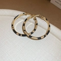 Detailopname van gouden oorringen met luipaardprint leertextuur op een witte achtergrond - Spliced Luipaardprint Creolen
