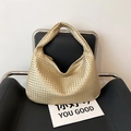 Gold woven hobo handbag with intrecciato texture displayed on a modern black leather chair - Gold