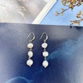 Détail de boucles d'oreilles pendantes avec trois perles baroques sur fond marbre bleu foncé - Boucles d'oreilles à crochet - 3 perles d'eau douce / Or