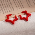 Detail of red frosted star earrings with silver posts on a textured white surface - Red Star