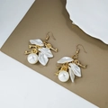 Detalle de pendientes vintage con pétalos blancos, perlas y llaves doradas sobre cuero - Llave