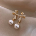 Elegante goldene Schleifenohrringe mit funkelnden Strasssteinen und weißen Perlen - Goldene Perlenschleife
