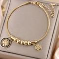 Detailed close-up of golden clover charms and snake chain on a gray jewelry box - Gold B-251G (Black/Solid Clover)