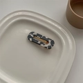 Detail of a marble pattern acetate hair clip on a white ceramic plate with soft shadows - Cow Pattern Square