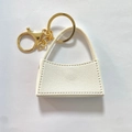 Dettaglio portachiavi mini borsa in pelle bianca con accessori dorati e chiusura a scatto - Bianco