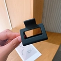 Close-up of a small matte black square hollow hair claw clip for elegant hair styling - Black