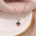 Macro shot of rose gold four-leaf clover necklace on white porcelain and pink silk - Black Four-leaf Clover