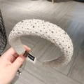 Nahaufnahme des dicken Strickstirnbands in Creme mit Champagner-Strasssteinen und Label - Creme