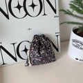 Detail of floral corduroy drawstring storage bag with cream cotton rope in a lifestyle setting - Black Small