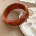 Detail view of faceted amber resin bangle featuring marble textures and glossy finish - Amber Orange Marble